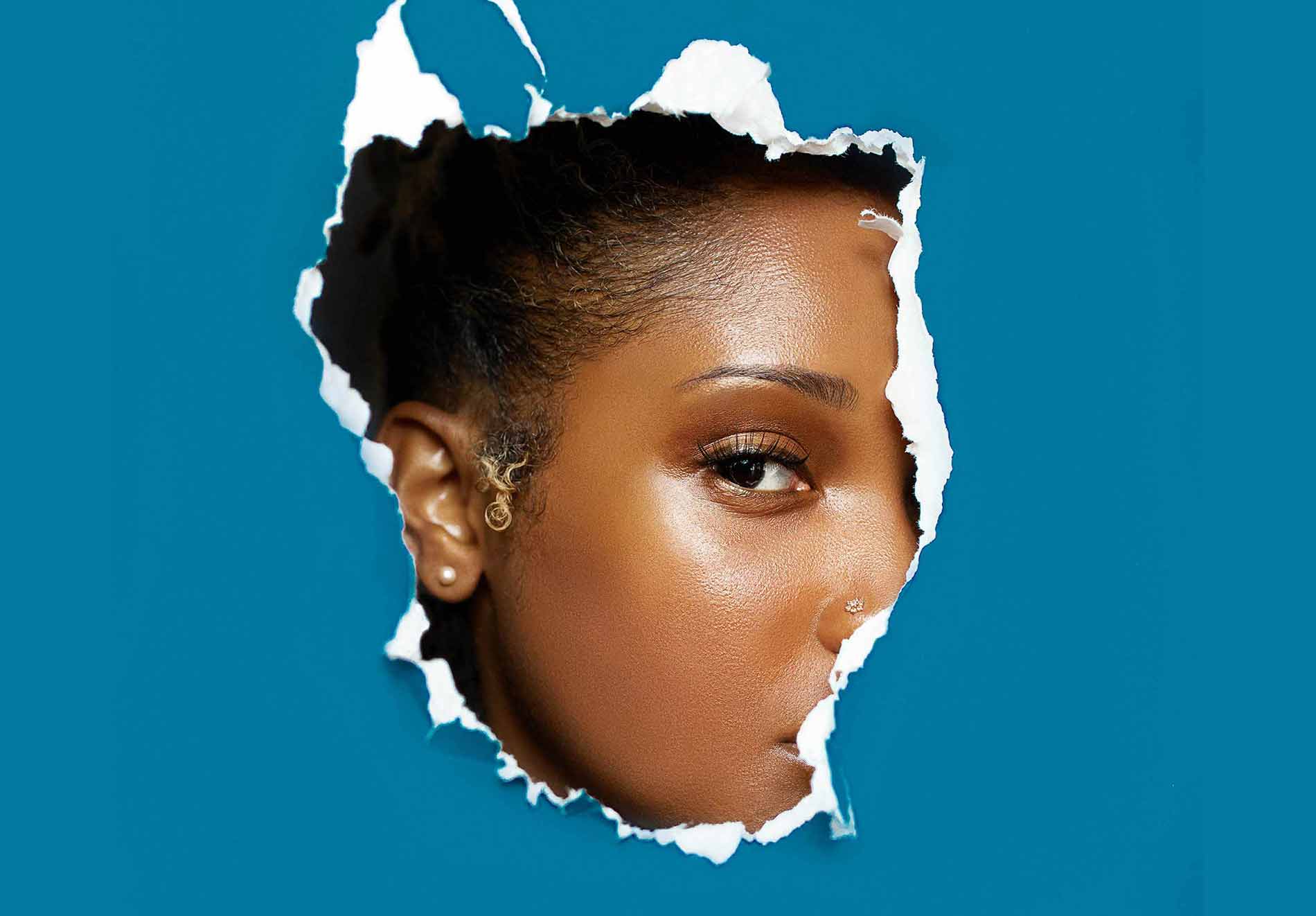 Woman Revealing Her Face through Ripped Paper